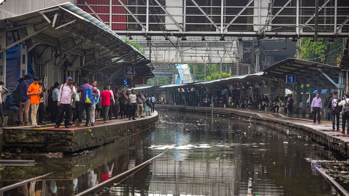 Passengers wait for trains at a waterlogged railway station, during rains in Mumbai.