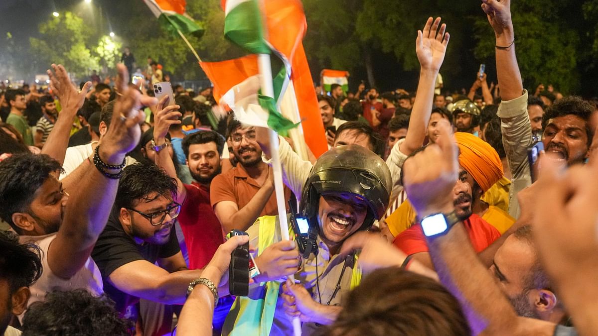 A cop celebrates with ardent cricket fans at the India Gate after India won the T20 World Cup 2024, in New Delhi.