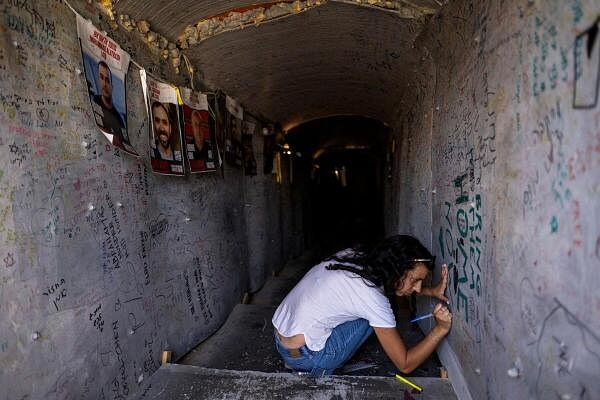 A woman writes a message at a mock tunnel in a plaza now dubbed as “Hostages Square” in solidarity with hostages kidnapped during the deadly October 7 attack on Israel by Hamas, in Tel Aviv, Israel, June 30, 2024.