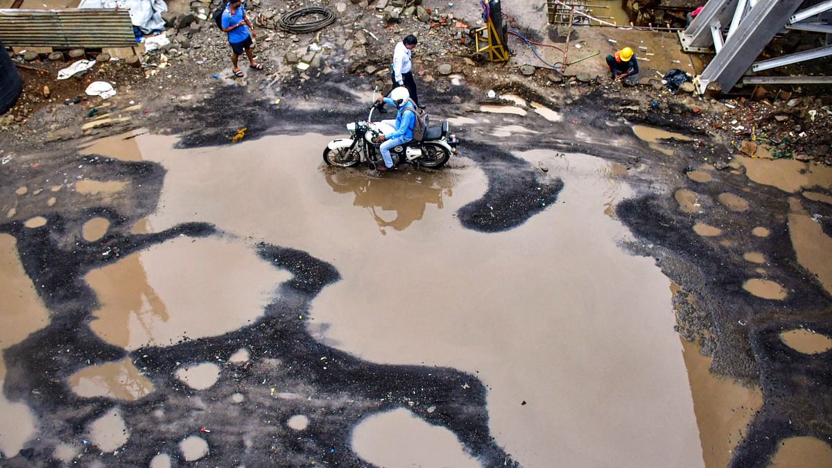 A motorcycle moves on a road wrecked by rainfall at Dadar Station in Mumbai.