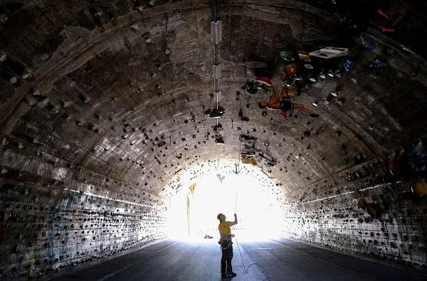 David Sanchez, 18, climbs helped by Carlos Gallardo, 65, at the wall of the Foixarda tunnel, which was transformed from a former road tunnel into an urban, free-to-use climbing gym open at all times, equipped with thousands of holds, in Barcelona, Spain