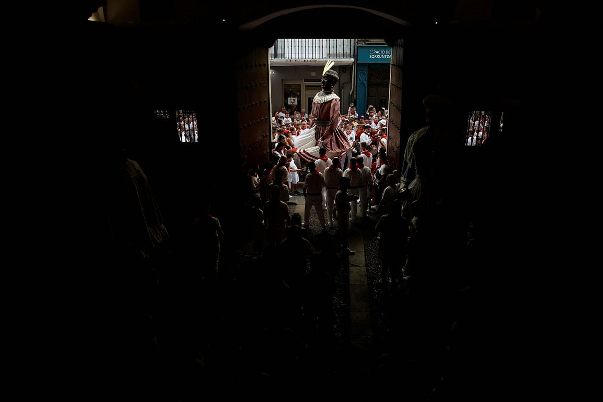 People watch as members of the San Fermin festival's "Comparsa de gigantes y cabezudos" (Parade of the Giants and Big Heads) prepare to take a break, in Pamplona, Spain, July 11, 2024.