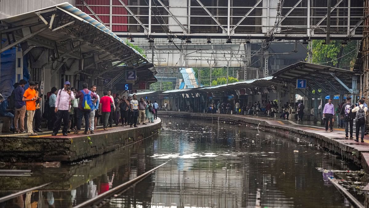 Passengers wait for trains at a waterlogged railway station during rains in Mumbai.