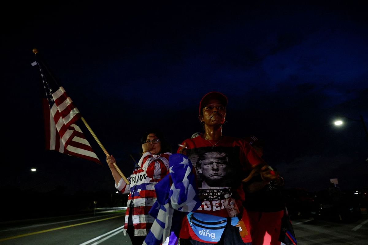 A person holds the U.S. flag after Republican presidential candidate and former US President Donald Trump was injured when shots were fired, in Palm Beach.