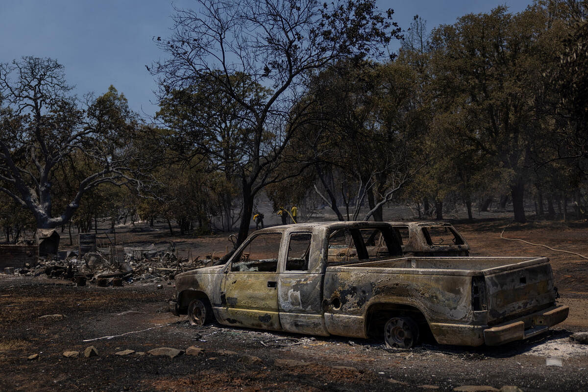 Firefighters work near burned vehicles after the Thompson fire affected a neighborhood near Oroville, California.