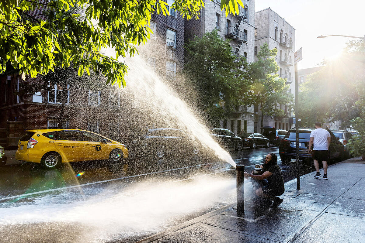 A man plays with an open hydrant during a hot and humid day in the Bronx borough of New York, US.