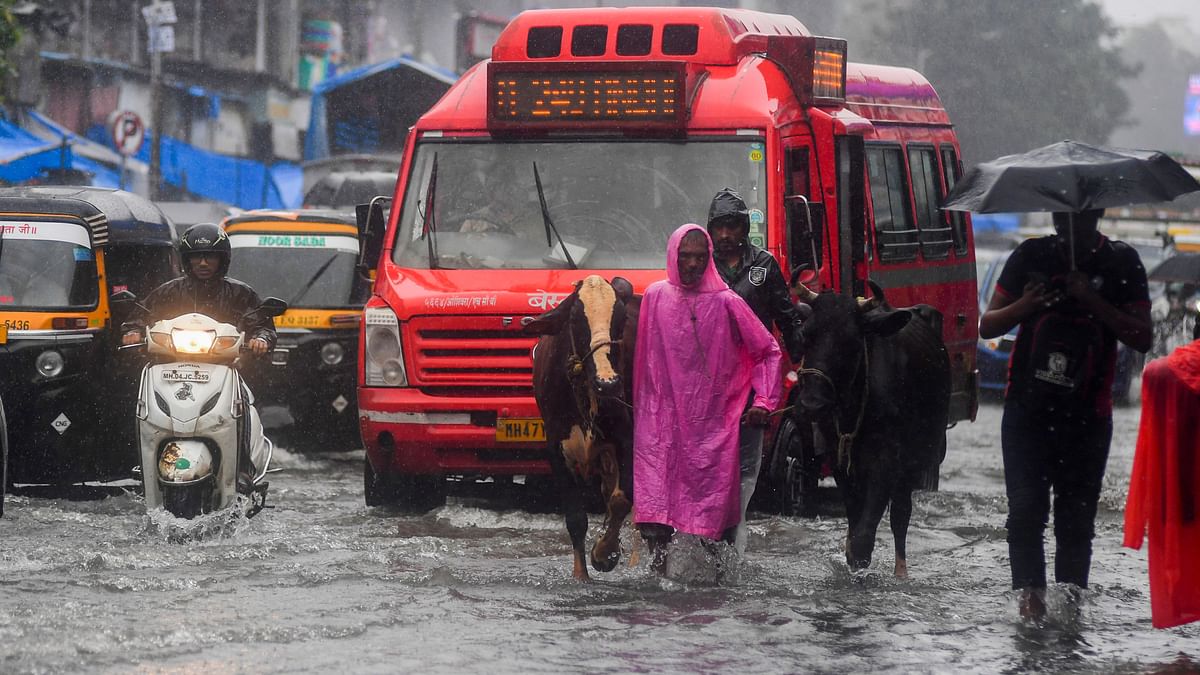 People walk through the waterlogged SV Road in Andheri West after heavy rainfall in Mumbai.