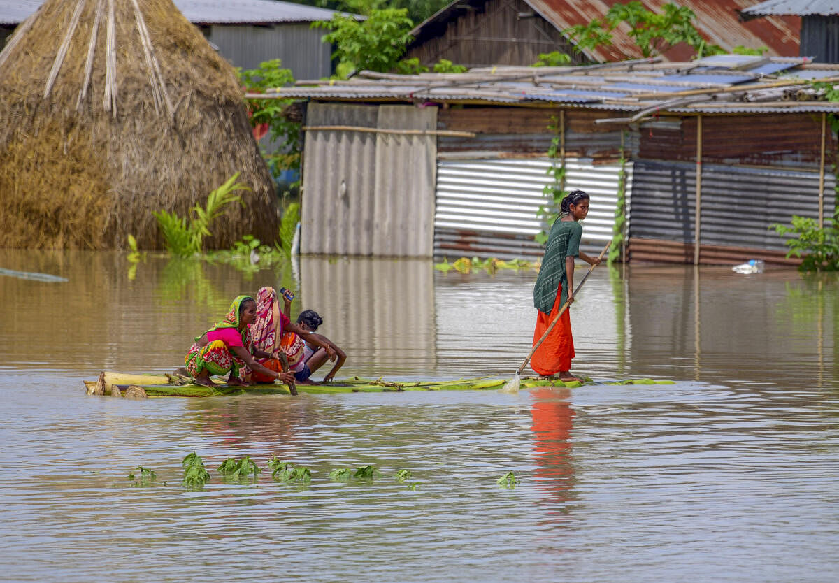 Women use a makeshift raft to cross flood waters, in Kamrup district.