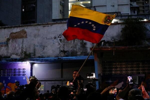 A man waves a Venezuelan flag near a polling station during the country's presidential election, in Caracas, Venezuela July 28, 2024.