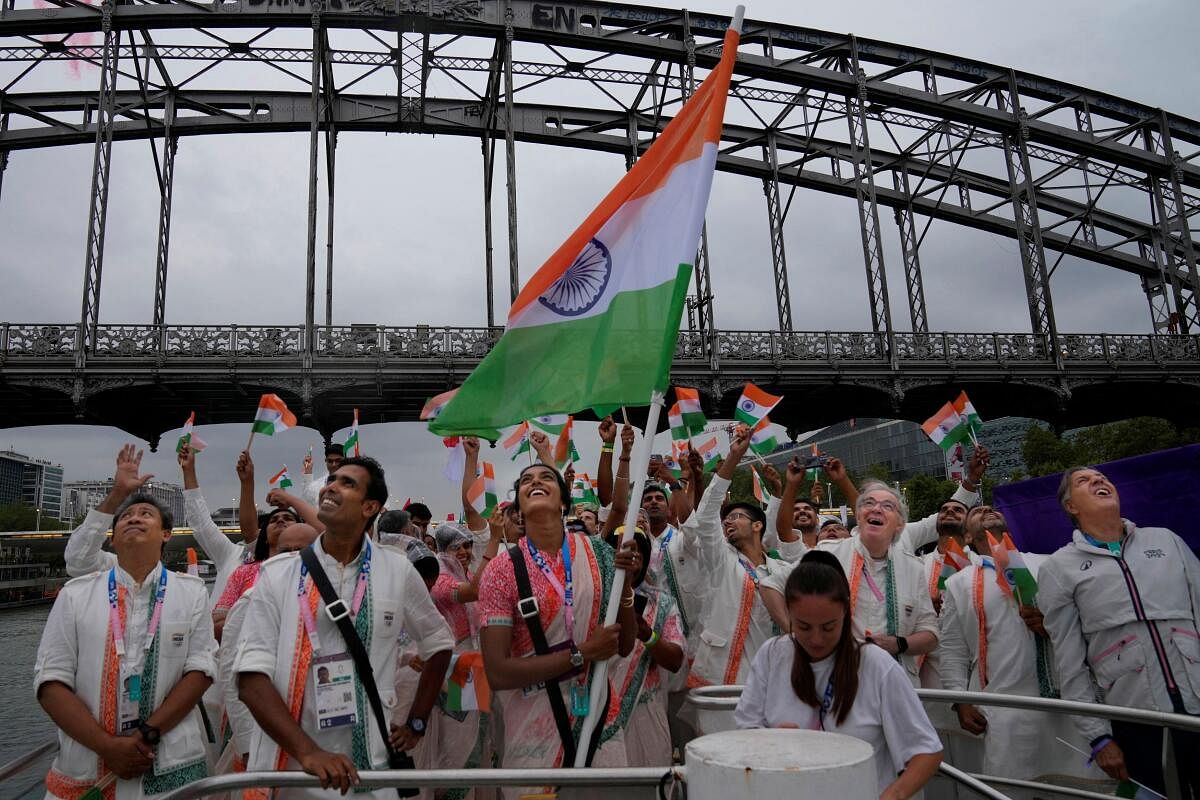 Indian athletes wave the Tricolour from a boat on the Seine River in Paris, France.