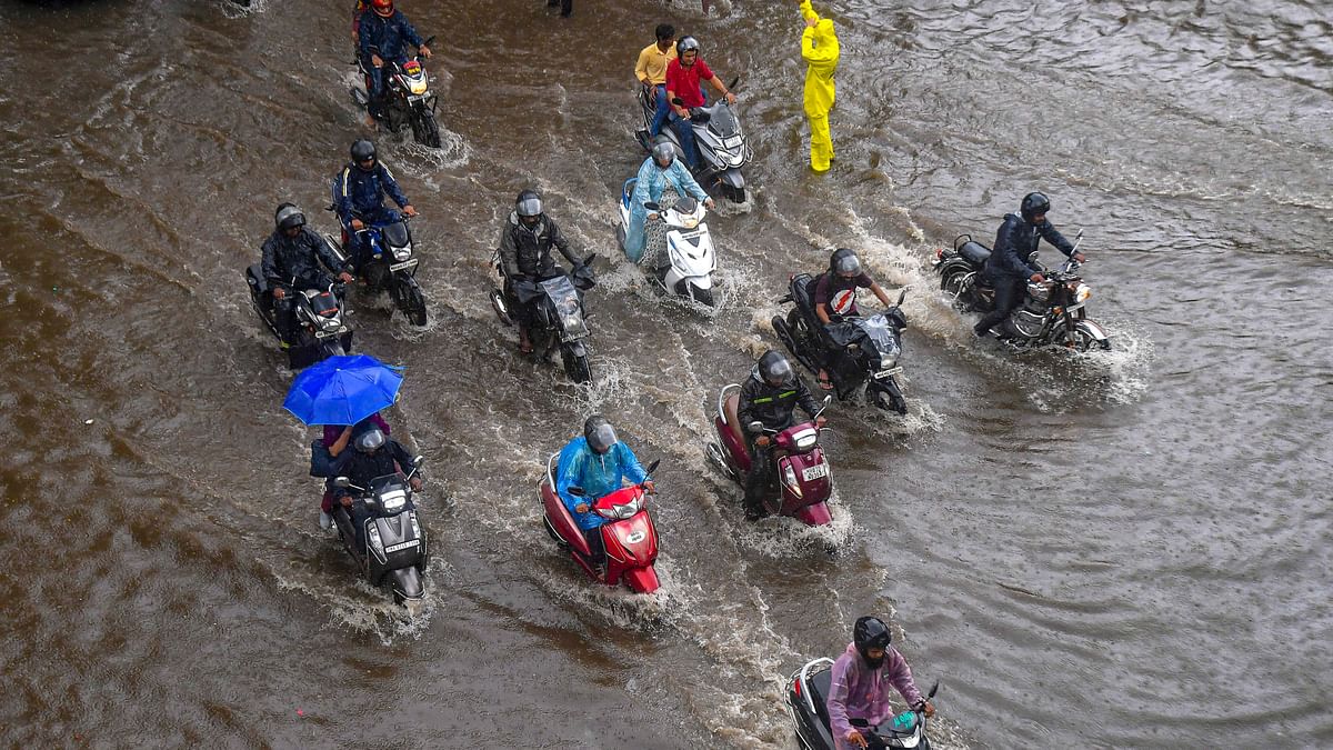 Commuters wade through a waterlogged street following rains in Mumbai.