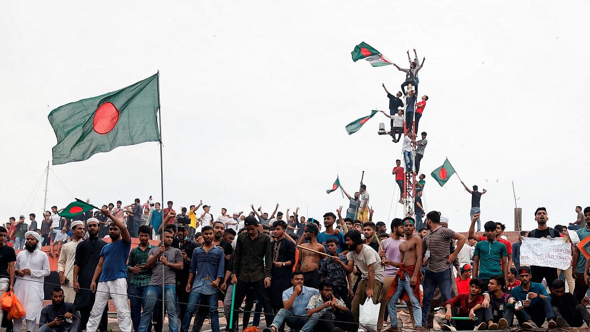 People wave Bangladeshi flags on top of the Ganabhaban, the Prime Minister's residence, as they celebrate the resignation of PM Sheikh Hasina in Dhaka, Bangladesh.