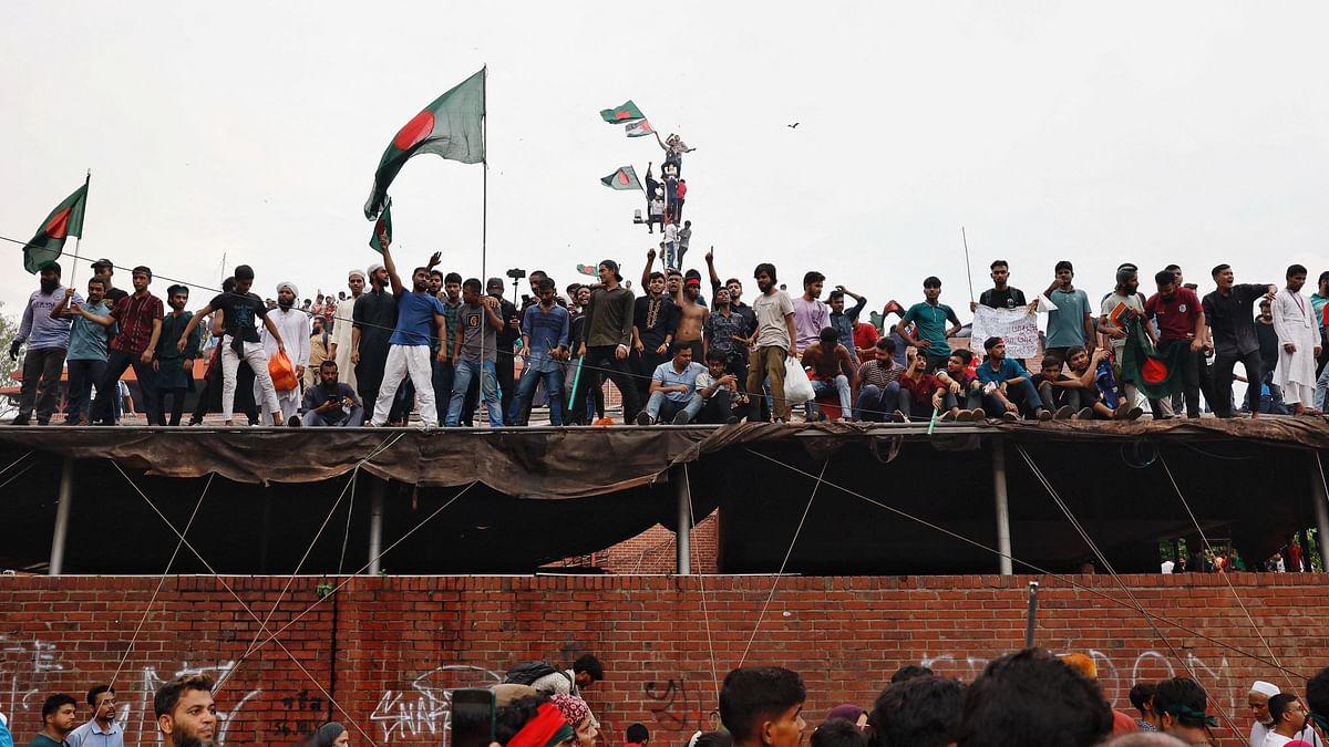 People wave Bangladeshi flags on top of the Ganabhaban, the Prime Minister's residence.