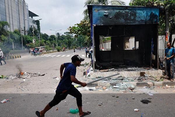 A demonstrator runs next to a vandalised police box during a protest demanding the stepping down of Bangladeshi Prime Minister Sheikh Hasina, following quota reform protests by students, in Dhaka, Bangladesh, August 4, 2024.