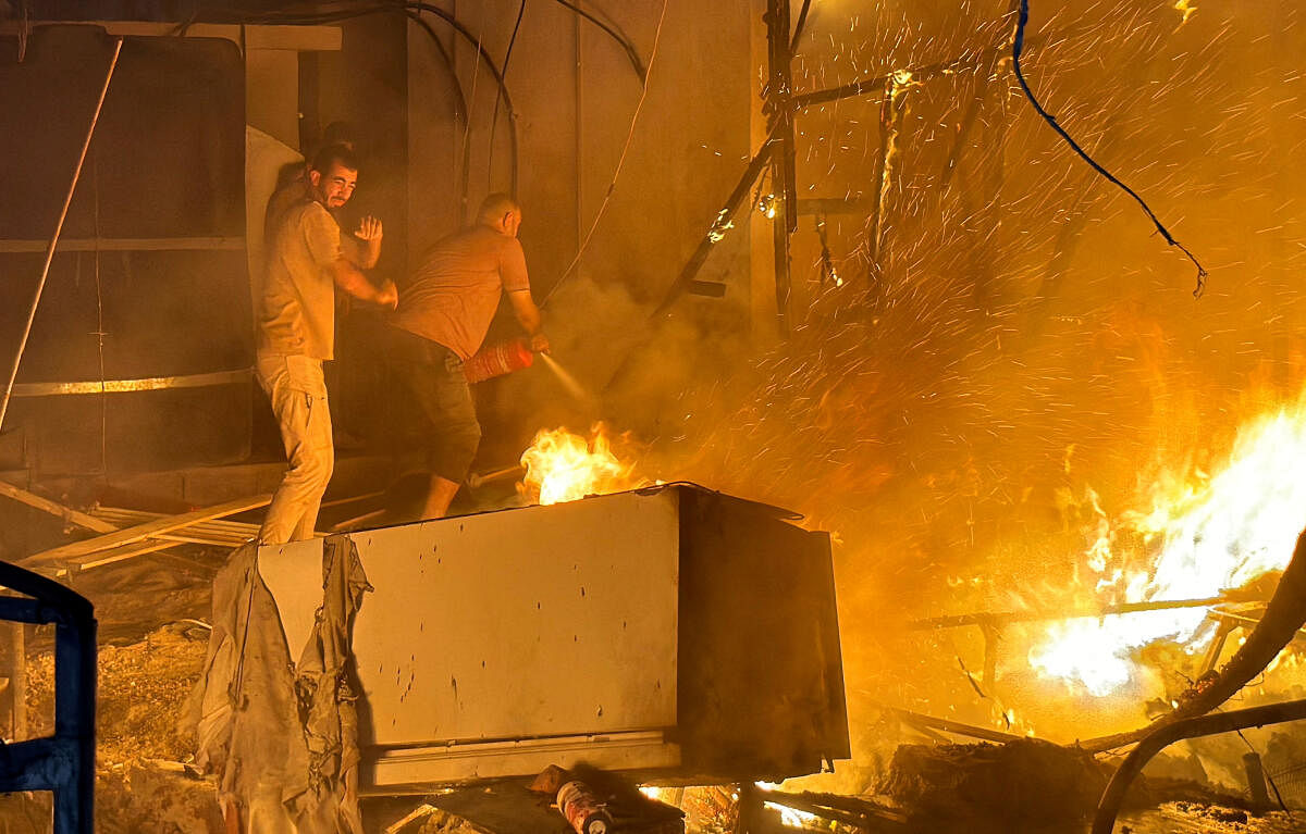 Palestinians work to extinguish a fire at the site of an Israeli strike on a tent camp for displaced people, amid the Israel-Hamas conflict, in Deir Al-Balah in the central Gaza Strip, August 4, 2024.