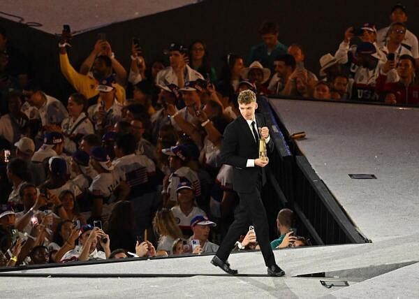 Leon Marchand of France holds the Olympic flame during the closing ceremony.