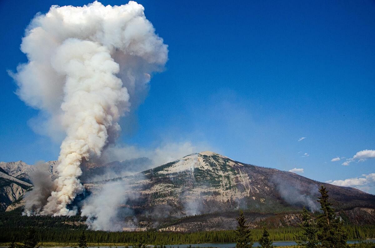 A plume of smoke rises as the Jasper Complex Wildfire continues to burn in Jasper National Park in Canada. 