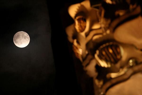 A supermoon, known as the blue moon and "Sturgeon Moon", rises next to the Casa Batllo, designed by Catalan architect Antoni Gaudi, in Barcelona, Spain.