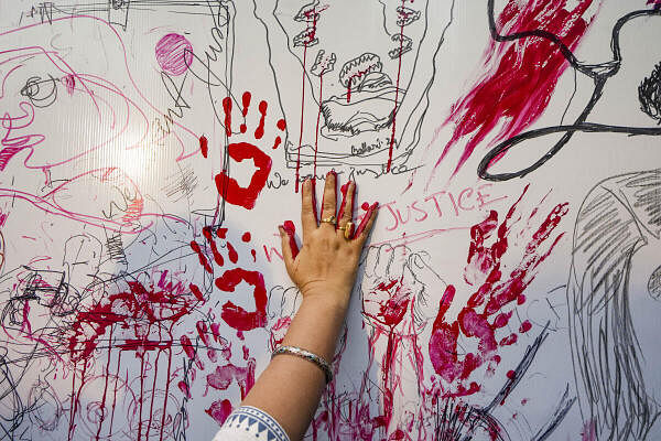 An artist puts her handprints on a wall during a protest against the alleged sexual assault and murder of a postgraduate trainee doctor, at Academy of Fine Arts, in Kolkata.