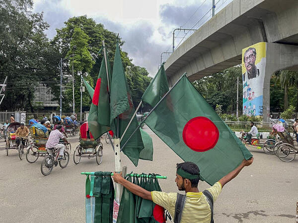 A flag-seller stands on the periphery of a memorial site, overlooking the tainted mural of first president of Sheikh Mujibur Rahman on the pier of a metro line, days after the anti-government protests that ousted the then Bangladesh prime minister Sheikh Hasina, near Dhaka University.