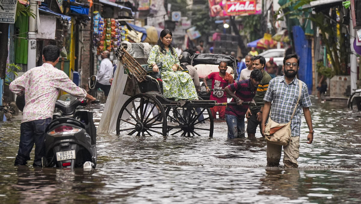 A rickshaw puller carries a passenger through a waterlogged road after heavy rainfall, in Kolkata.