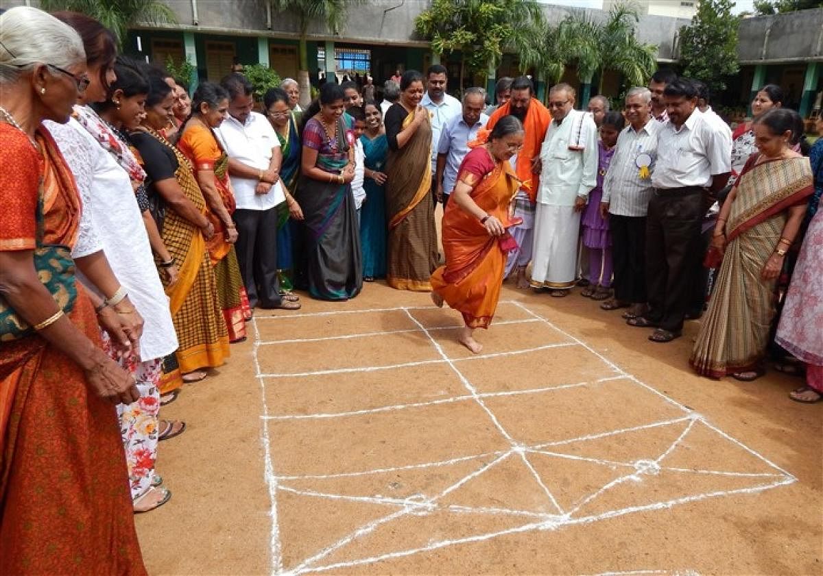 A woman plays ‘kunte bille’ at a fair in Mysuru.