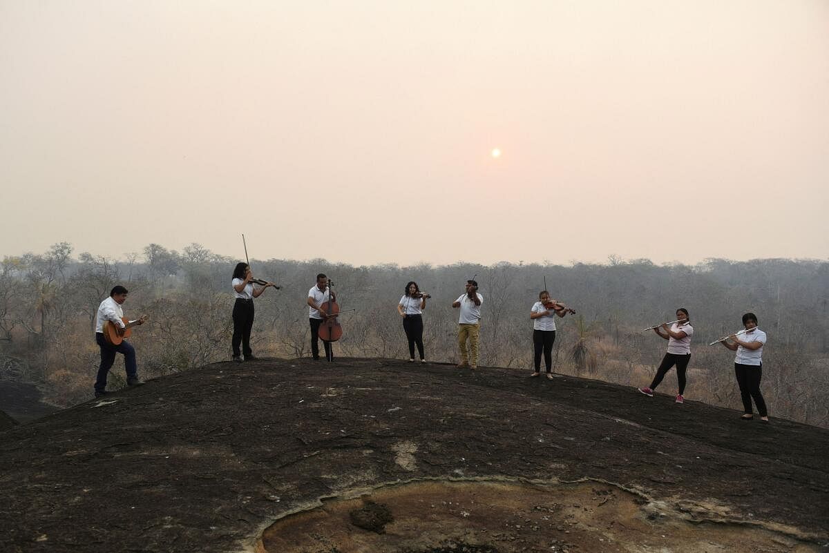 Members of the Misional Padre Martin Schmid Music School play their instruments to bring attention to the smoke from the wildfires in the area, in Concepcion, Bolivia.