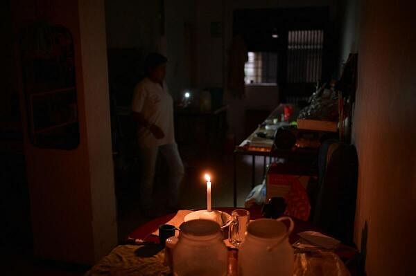  woman uses a candlelight and the light from her mobile phone to illuminate her house during a power outage affecting Caracas and other regions of the country, in Caracas.