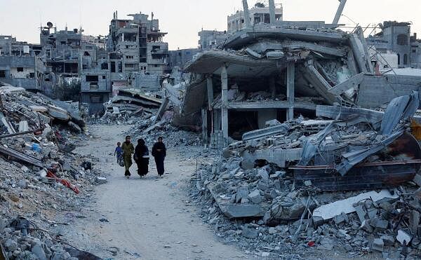 Palestinian walk amidst the rubble of buildings destroyed after an Israeli strike, amid the ongoing conflict between Israel and Hamas, in Khan Younis, in the southern Gaza Strip.