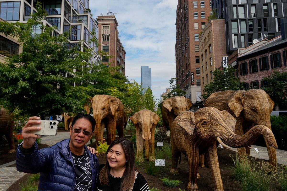 People pose for a selfie in front of life sized Indian elephant structures which are standing in the Meatpacking district as part of the public art installation ‘The Great Elephant Migration’ in New York City, US, September 06, 2024.