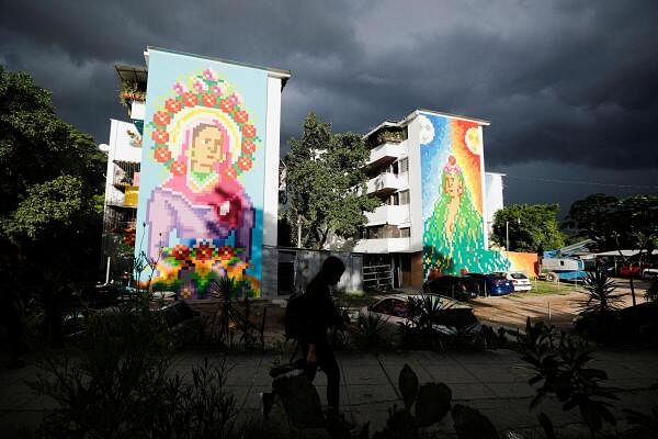 A woman walks past murals titled "Cryptomadonna of Peace" and "Pachamama" by Italian artist Beatrice Vigoni, part of the Zacamil Project, an initiative led by a Salvadoran foundation that seeks to decorate humble and once violent communities with art, in Mejicanos, El Salvador July 26, 2024. 