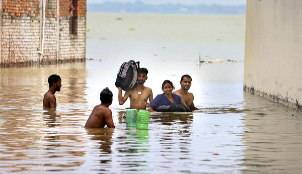 People living in low laying areas shift their belongings to a safer place after a rise in the water level of Rivers Ganga and Yamuna following heavy rains, in Prayagraj, Sunday, Sept. 15, 2024.