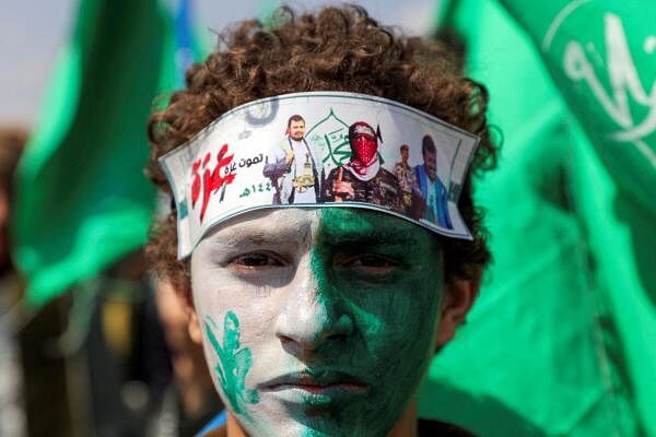 A Houthi supporter with a headband featuring photos of Houthi leader, Abdul-Malik al-Houthi, and spokesman for the Hamas military wing, Abu Ubaidah, attends a rally to mark the anniversary of the birth of the Prophet Mohammad and to show solidarity with Palestinians in the Gaza Strip, in Sanaa, Yemen