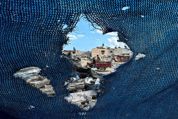 A Palestinian drives a car through rubble, past a torn tent, during ongoing clashes between Israel and Hamas in Khan Yunis, southern Gaza Strip.