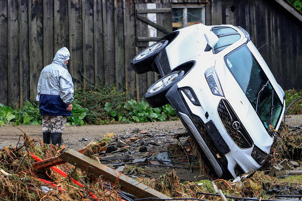 A person stands next to an overturned car after heavy rains in Bela pod Pradem, near Jesenik, Czech Republic.