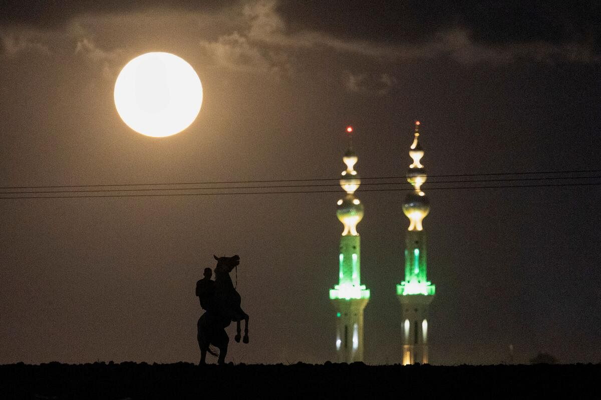 A Bedouin rides his horse as the Harvest Supermoon rises over the city of Rahat, southern Israel, September 18, 2024.