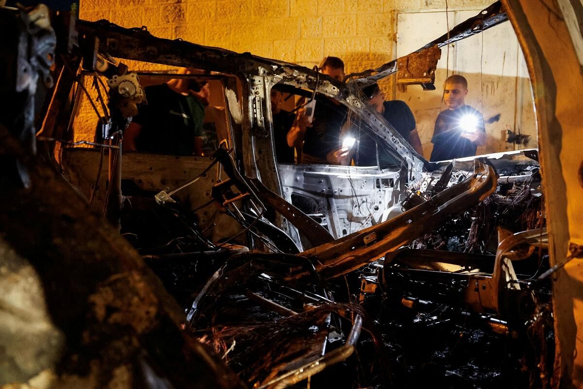 Palestinians inspect a car that was destroyed in an Israeli airstrike, in Qabatya, near Jenin, in the Israeli-occupied West Bank, September 19, 2024.