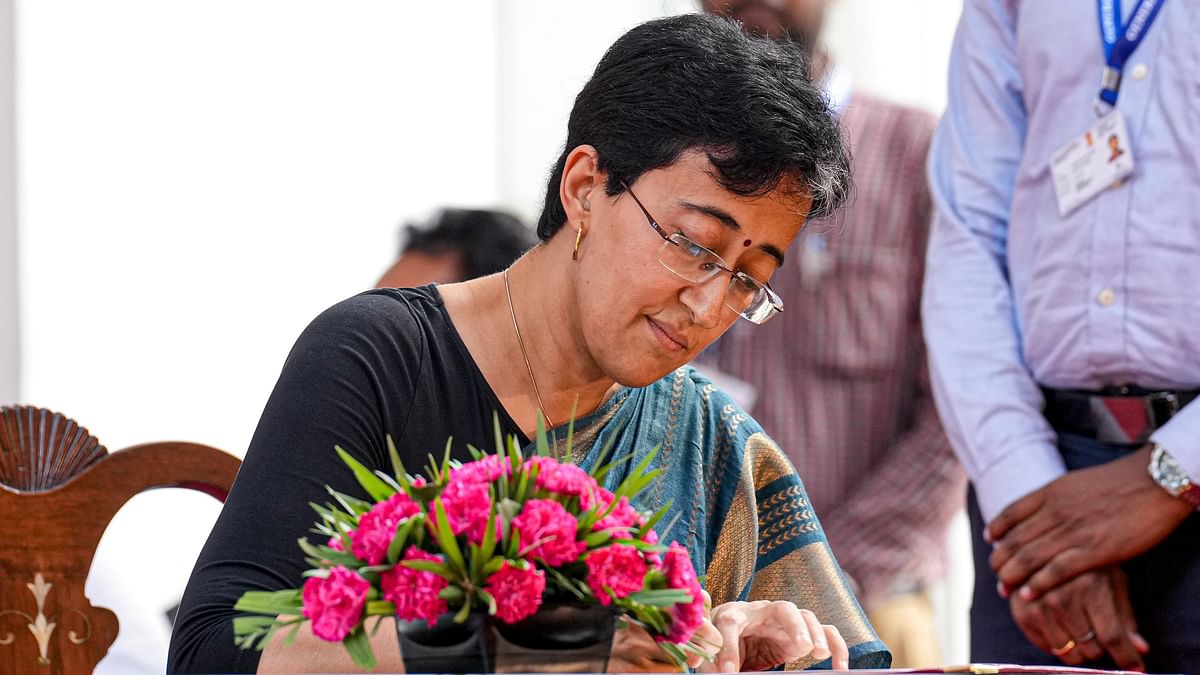 Atishi signs documents after taking oath as Chief Minister of Delhi during a ceremony at Raj Bhavan, in New Delhi, Saturday