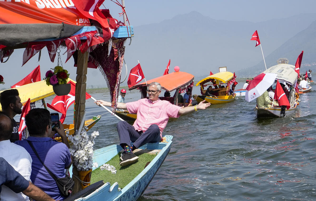 National Conference Vice President Omar Abdullah holds the party flag as he takes a 'shikara' ride during a rally ahead of second phase election of Jammu and Kashmir Assembly, at Dal Lake.