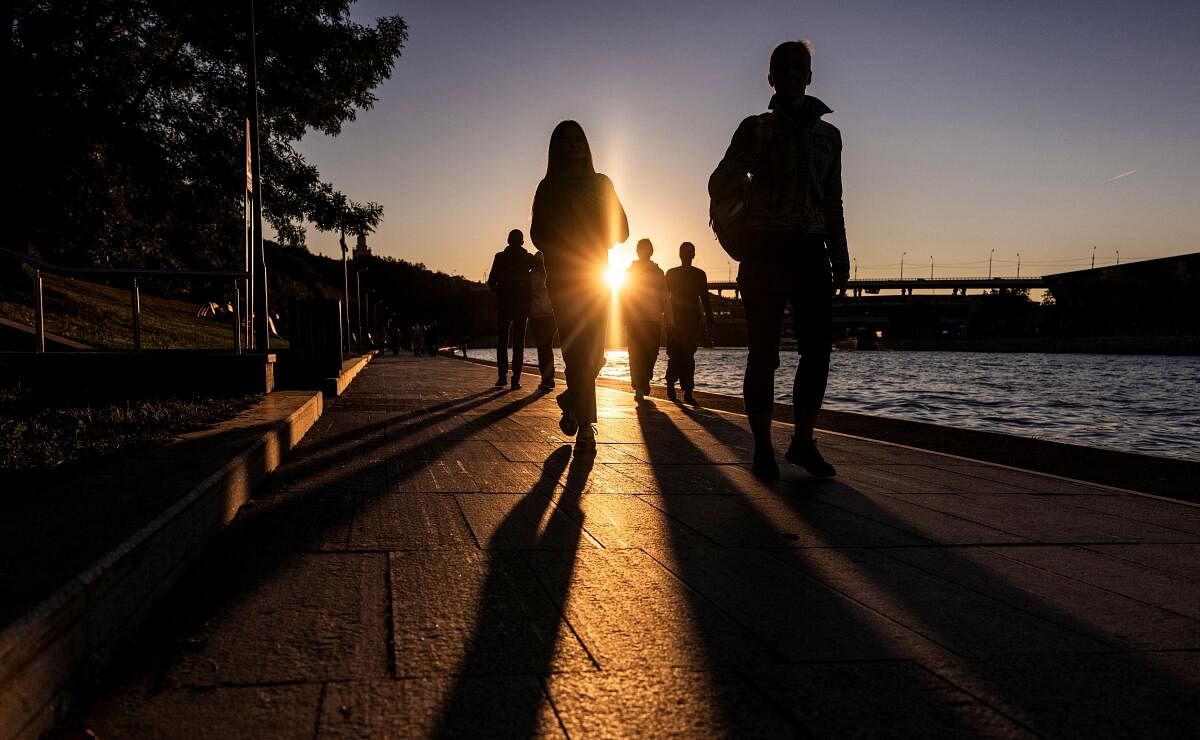 People walk on the embankment of Moskva river during warm autumn sunset in Moscow, Russia