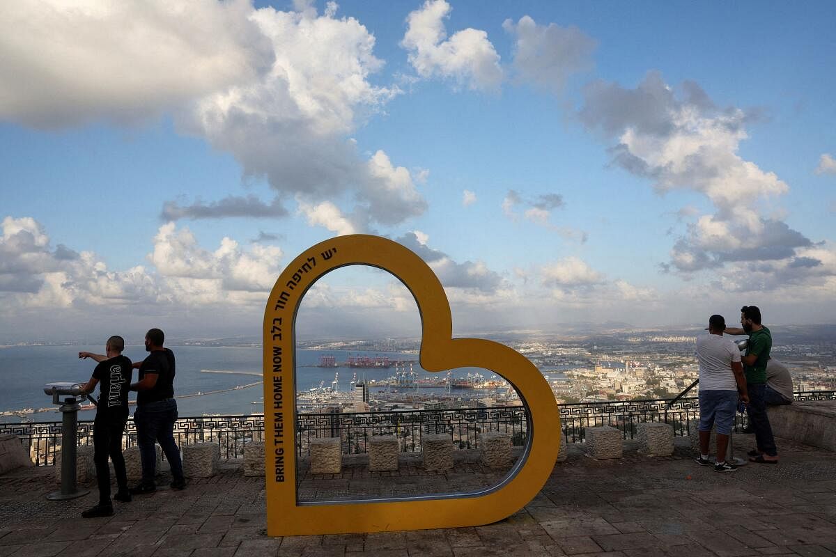 People look over the city of Haifa, next to a heart shape installation that reads ''Bring them home now - Haifa has a hole in its heart'', amid cross-border hostilities between Hezbollah and Israel.