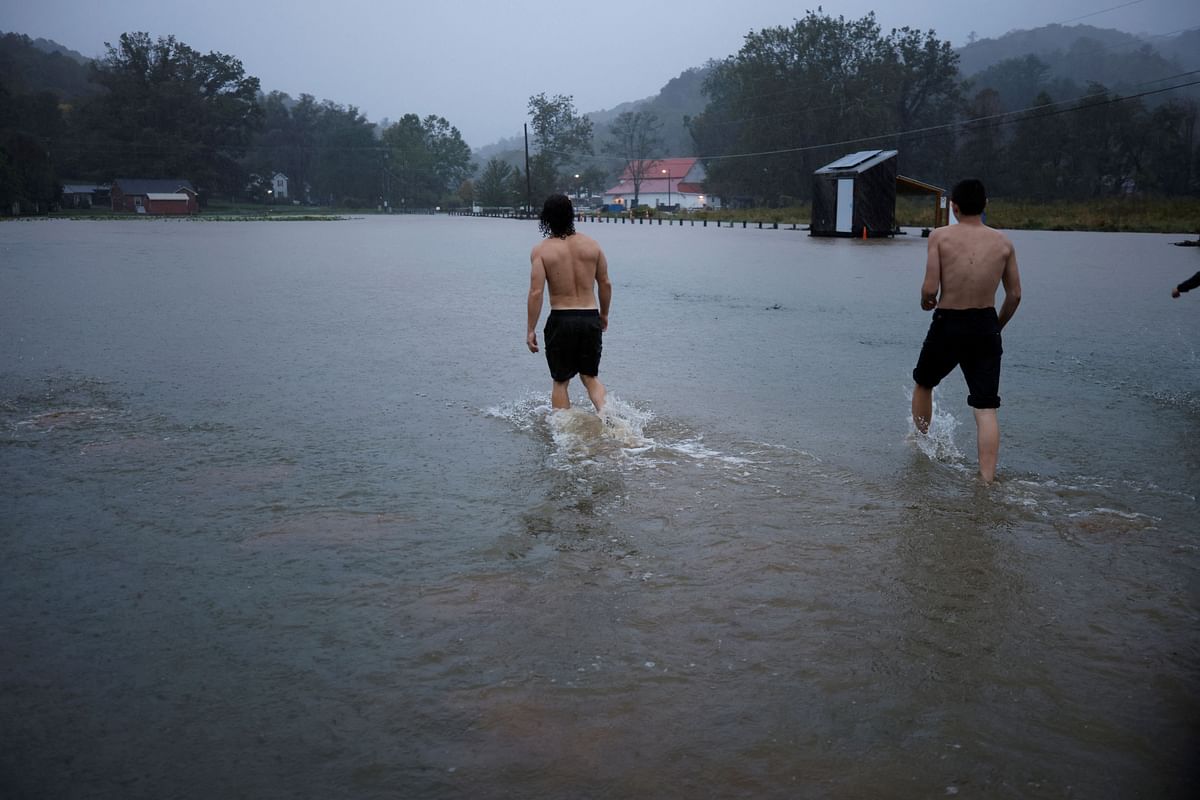 Residents walk through a flooded field as they play outside in the rain, as Hurricane Helene approaches in the North Carolina mountains, in Valle Crucis, North Carolina, US September 26, 2024.  