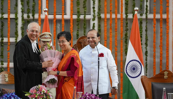 Delhi Chief Minister Atishi greets Justice Manmohan after he took oath as the Chief Justice of the Delhi High Court during a ceremony at the Raj Niwas, in New Delhi, Sunday, Sept. 29, 2024. Delhi Lieutenant Governor Vinai Kumar Saxena is also seen.