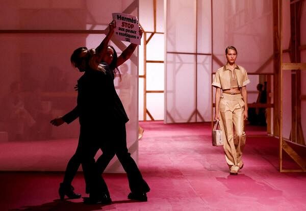 A protester holds a placard reading "Hermes stop exotic skin" as a model presents a creation by designer Veronique Nichanian as part of her Spring/Summer 2025 Women's ready-to-wear collection show for fashion house Hermes during Paris Fashion Week in Paris, France, September 28, 2024.