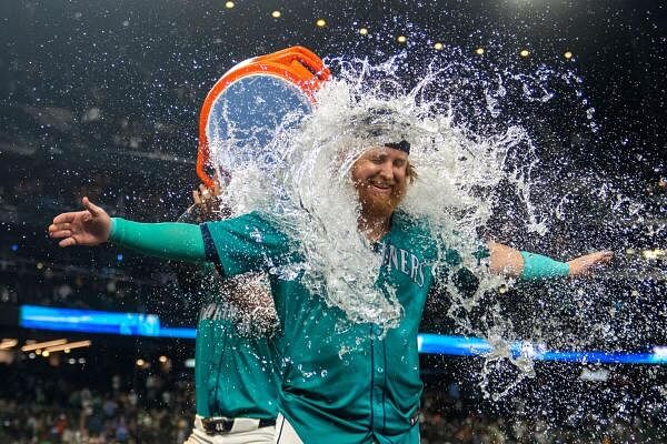 Seattle Mariners pinch hitter Justin Turner (2) is doused with water by centerfielder Julio Rodriguez (44) after a game against the Oakland Athletics at T-Mobile Park.