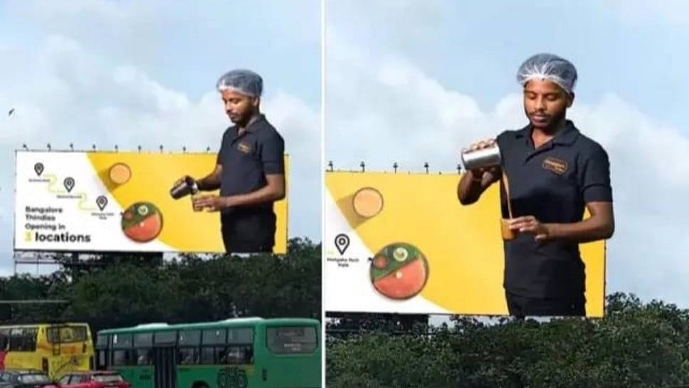 The advertisement features a man pouring hot coffee into a glass. Its three-dimensional effect makes it appear as if he is offering coffee to passing commuters.