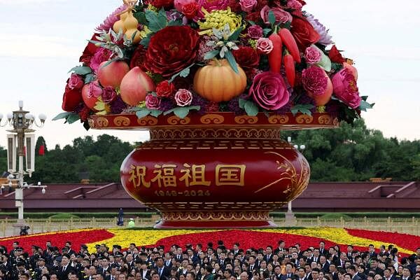 Attendees stand in front of a giant flower basket installation before a ceremony to commemorate Martyrs' Day, on the eve of the 75th founding anniversary of the People's Republic of China, on Tiananmen Square in Beijing, China.