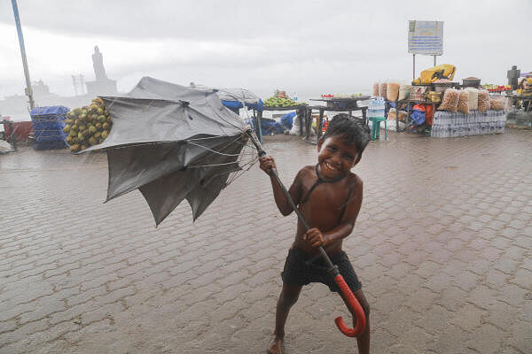 A child struggles to hold an umbrella amid strong winds and heavy rainfall, in Kanyakumari.