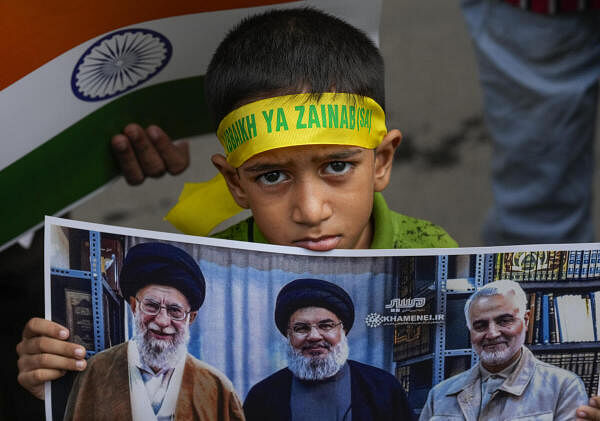 A young boy holds a picture of Iran's supreme leader Ayatollah Ali Khamenei, Hezbollah leader Sayyed Hassan Nasrallah and slain Iranian commander Qassem Soleimani during a peace rally by Shia Muslims against Israel, following Nasrallah's killing, in Chennai.