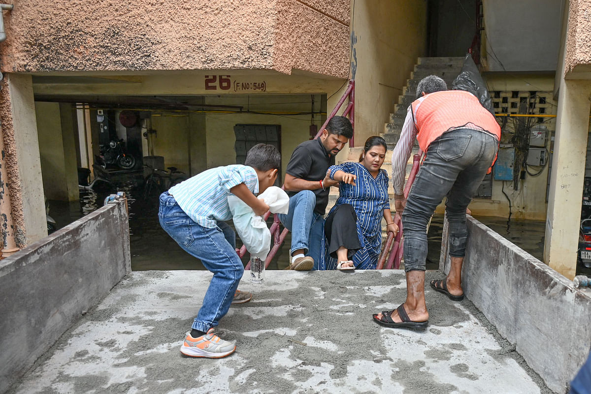 BBMP workers help residents of the Kendriya Vihar apartment complex in Yelahanka near Kogilu Cross to vacate their flooded homes on Sunday. DH Photo/SK Dinesh